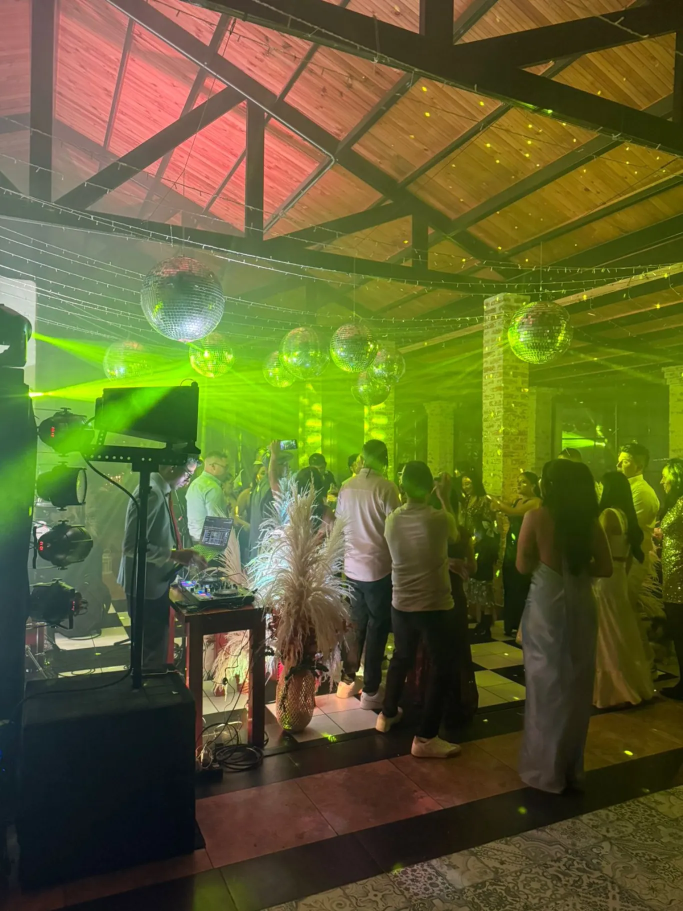 Iluminación láser verde y esferas disco en la pista de baile de un evento social en Bogotá